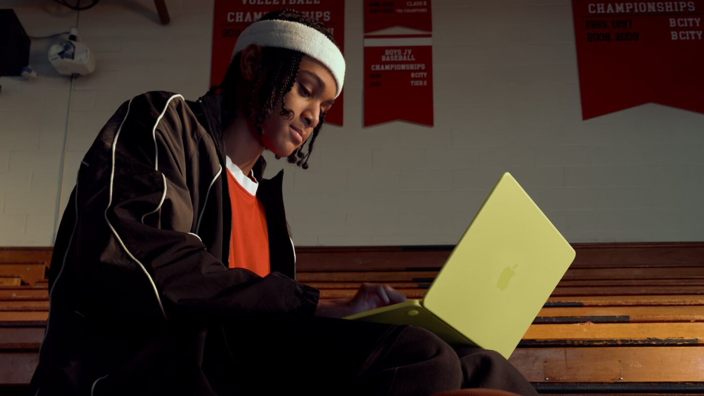 Photo of a person using a MacBook Neo in a school gym, used to illustrate a story about Mac supply constraints