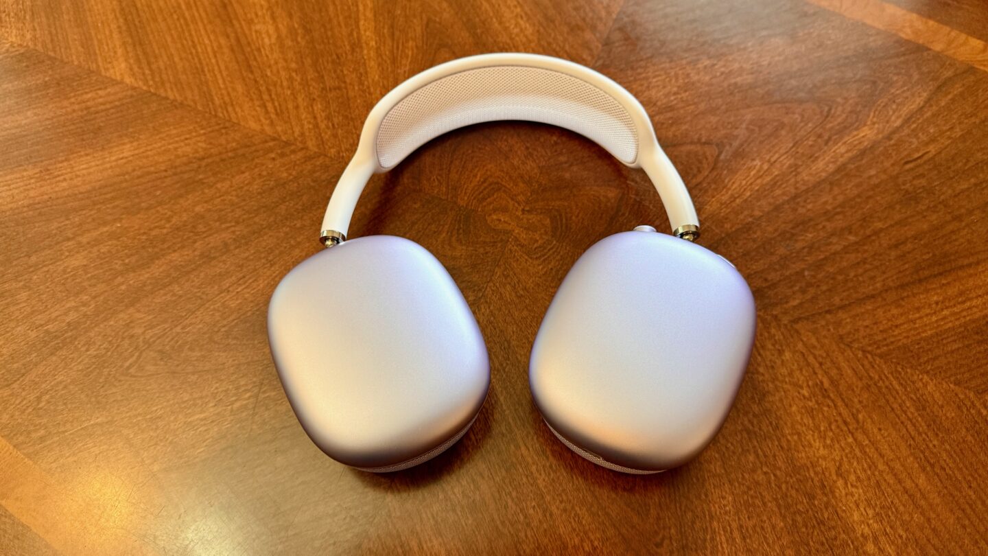 Purple AirPods Max 2 on a wood table.