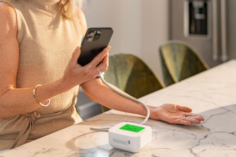 Woman taking her blood pressure reading and syncing results to her iPhone with iHealth Track blood pressure monitor