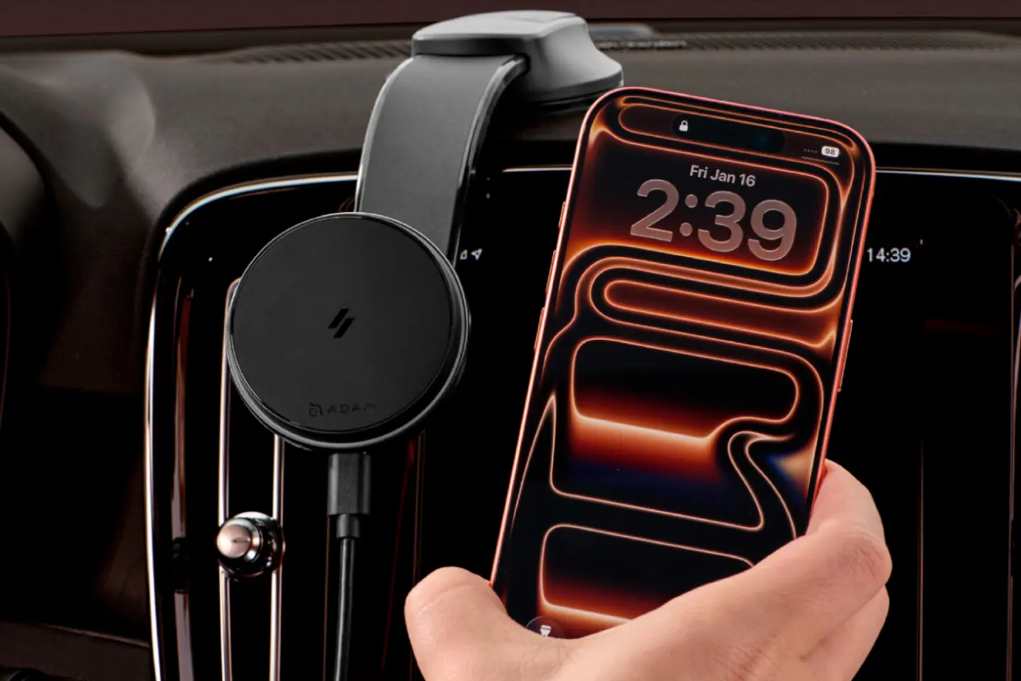 View of a car dashboard with an iPhone being held by a hand and a mounted magnetic iPhone car mount charger.