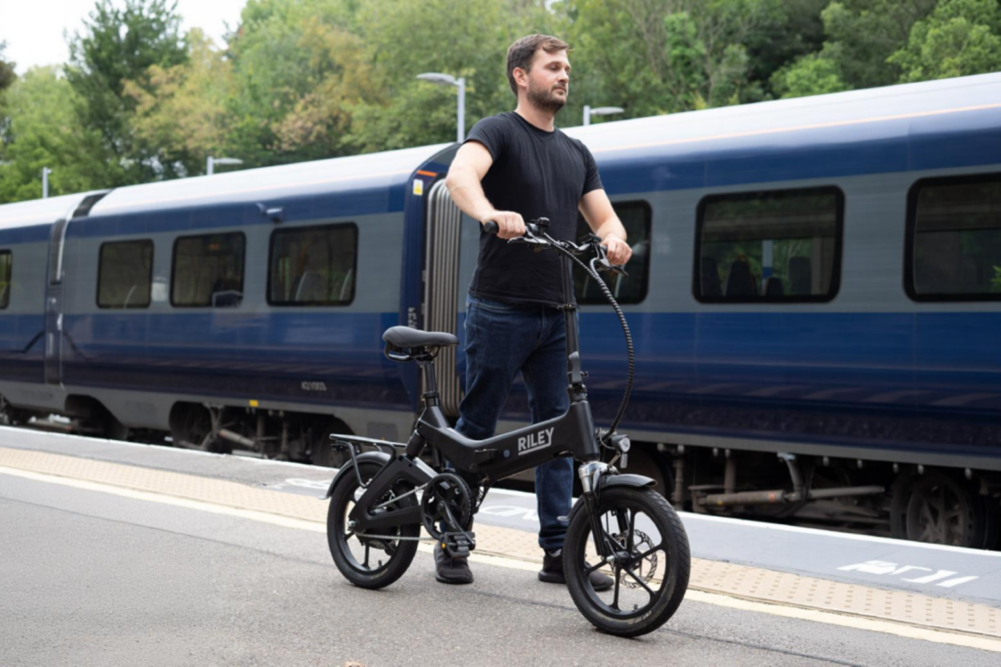 A man with his folding e-bike at a train station