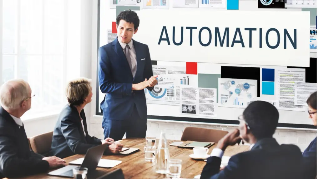 Photo of a man presenting the topic, automation, in front of people in a meeting room.