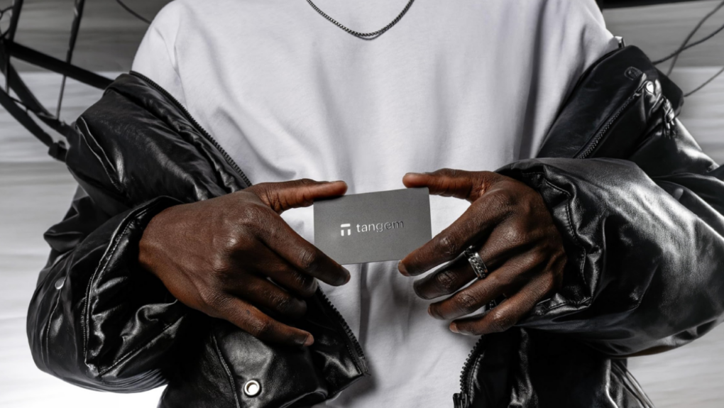Person wearing a white shirt and black leather jacket holding a digital wallet card with both hands
