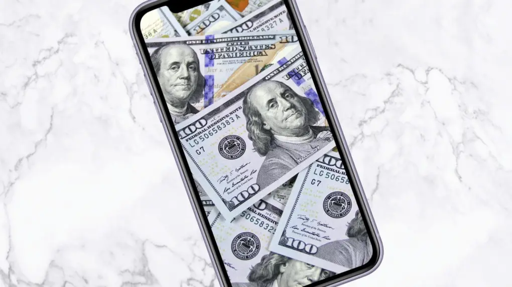 Image of an iPhone with $100 bills on the screen, used to illustrate a story about TSMC's price hikes on processors