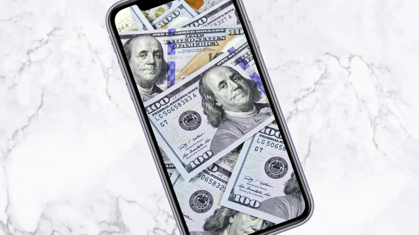 Image of an iPhone with $100 bills on the screen, used to illustrate a story about TSMC's price hikes on processors