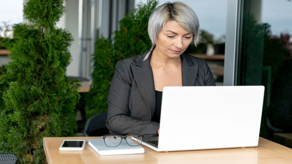 Woman sitting outside working on her white laptop device, using the Claude AI Professional Skills CPD Certification course bundle