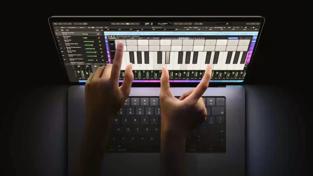 Photo of person using touchscreen MacBook Pro for music production, showing two hands touching the screen