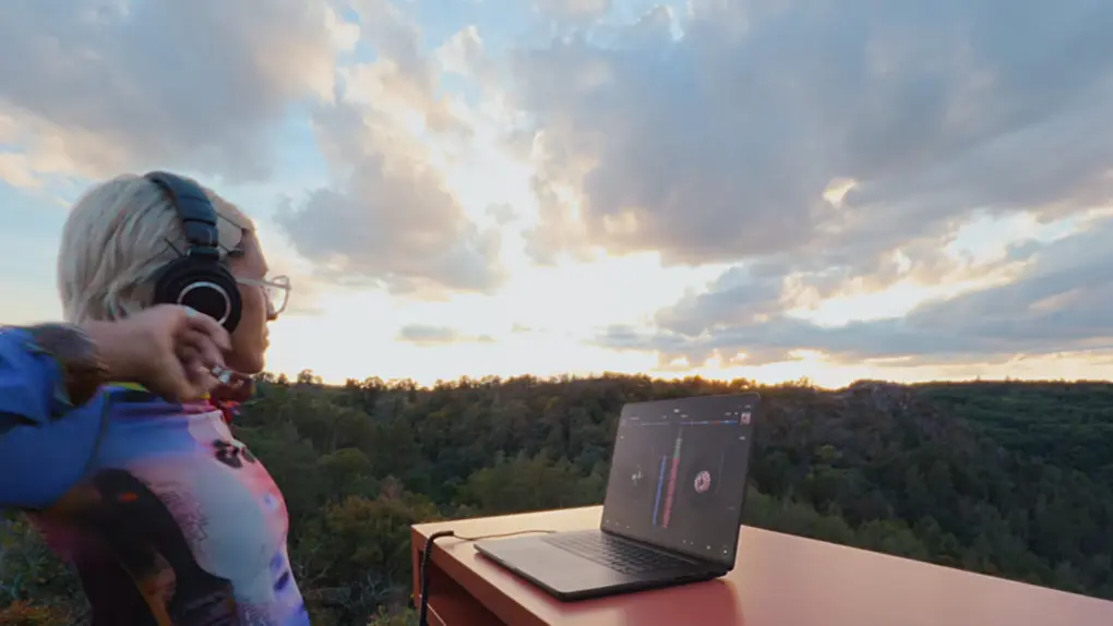 Still from Apple ad that shows a person using touchscreen MacBook Pro from a mountaintop