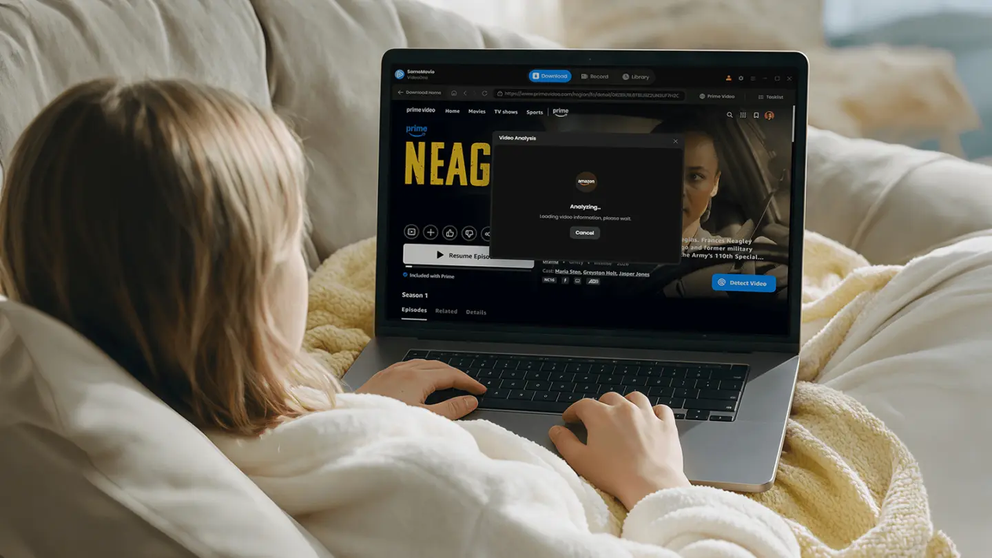 Woman on a couch downloading a video from a streaming service through the laptop