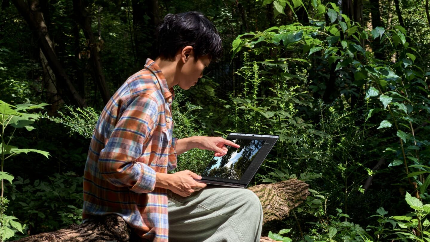 Touchscreen MacBook Pro in woods Photo of person using touchscreen MacBook Pro in woods